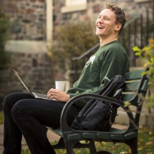 Benn Van Ryn using his laptop in the King's quad