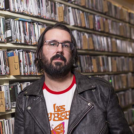 Trevor Murphy, standing in front of a shelf of records