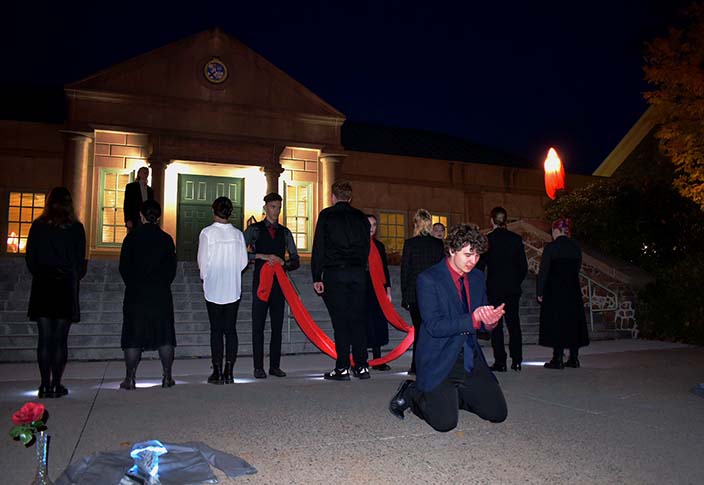 Students perform a play outdoors at night on the library steps