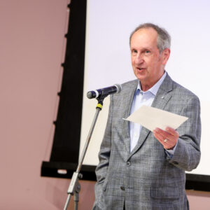 Fred Fountain stands at microphone to introduce the evening lecture